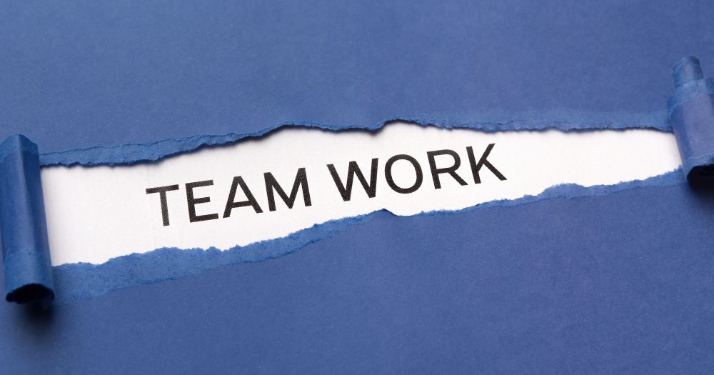 Text Team work on white background appearing behind torn blue paper